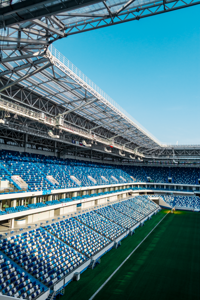 Spacious modern soccer stadium with blue seating and open sky view.